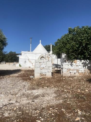 a stone building with a white tent in the background at Trullo Moi in Ostuni