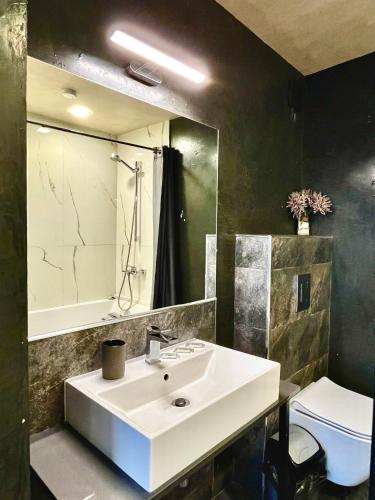 a bathroom with a white sink and a mirror at Damyanov House in Kazanlŭk