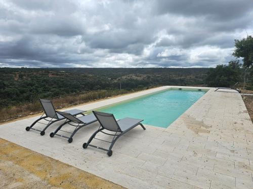 zwei Stühle neben einem Swimmingpool in der Unterkunft Casa de Mosqueirões in Santa Margarida da Serra