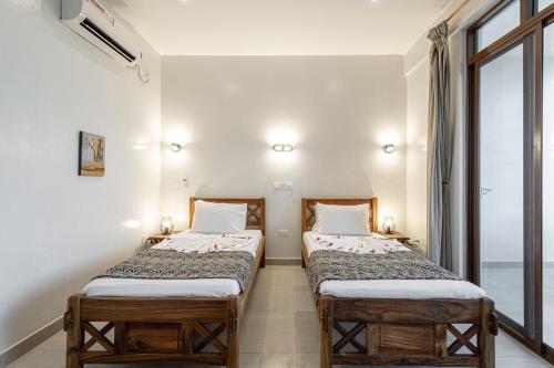 two twin beds in a room with a window at YU Resort in Msambweni
