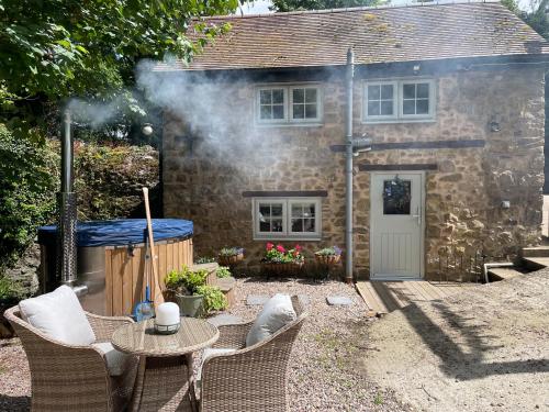 a stone house with a table and chairs in front of it at The Cider Press at Deep Filling Farm, woodland luxury in Gloucestershire