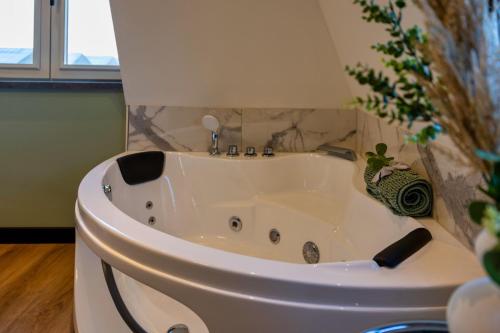 a white bath tub in a bathroom with a plant at Villa Savannah in Roelofarendsveen