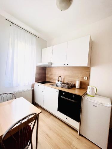 a small kitchen with white cabinets and a table at Apartman Zagreb Jarun in Zagreb