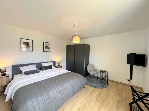 une chambre avec un grand lit et une chaise dans l'établissement Cosy 152 proche aéroport -gare-groupama stadium-lyon, à Colombier-Saugnieu