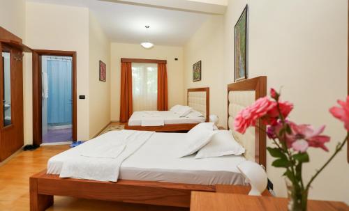 a bedroom with two beds and a vase with flowers at Hotel Kanione in Çorovodë