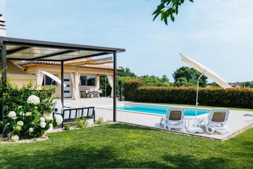 a house with a swimming pool and two lawn chairs at Villa Mila Rovinj in Rovinj