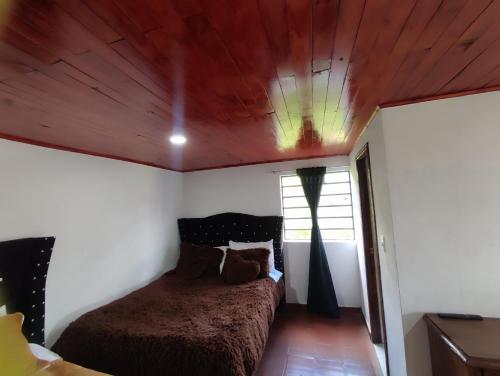 a bedroom with a bed with a wooden ceiling at Cabañas Casa Campo Guatavita in Guatavita