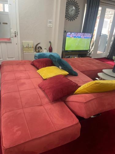 a large bed with red sheets and yellow pillows at Stylish Home Away From Home in Kent with Easy Access to London! in Wrotham