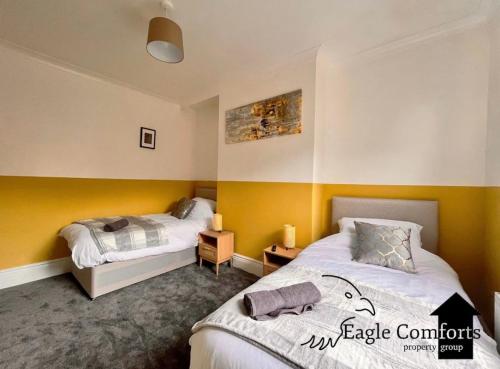 two beds in a room with yellow walls at 5 Bedroom House-20 percent off monthly stays in Neepsend