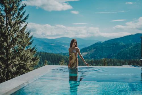 a woman standing in a swimming pool with mountains in the background at LUXGUT - Rebecca in Zmöllach
