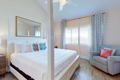 Un dormitorio con una cama blanca y una silla. en A1A South St Augustine 2 bedroom Oceanview Condo Sleeps 8, en Fort Matanzas