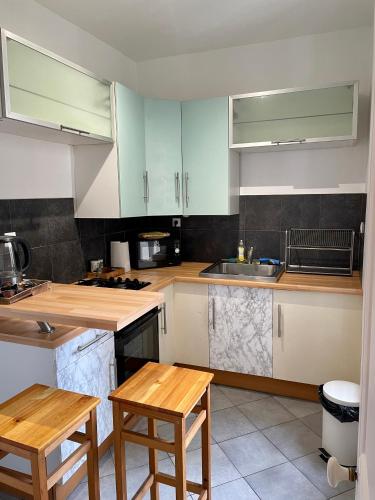 - une cuisine avec des placards blancs et des tables en bois dans l'établissement Akwaba Nancy, à Nancy