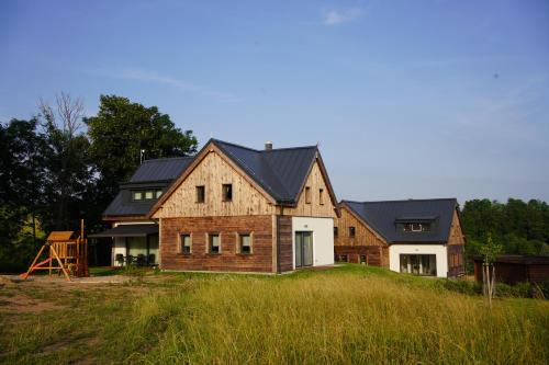a house with a black roof on top of a field at Rodinný apartmán Čistá in Cerny Dul