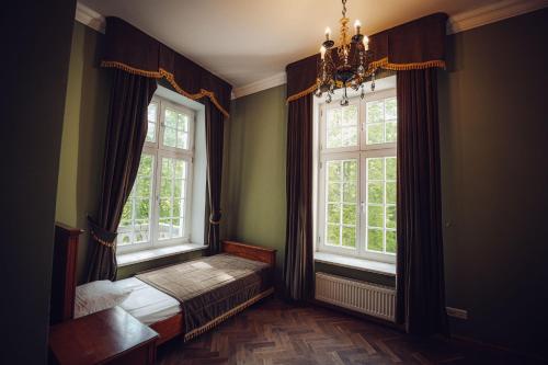 a bedroom with two windows and a bed and a chandelier at Pałac Borowa in Borowa