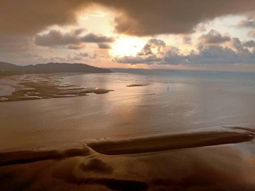 a view of a beach with the sun setting on the water at Imperium Residence House SEAVIEW at Swiss Belhotel in Kuantan