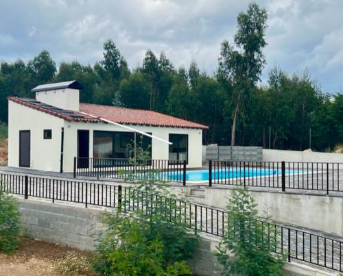 a building with a swimming pool next to a fence at Casa de Pedra in Pedrógão Grande