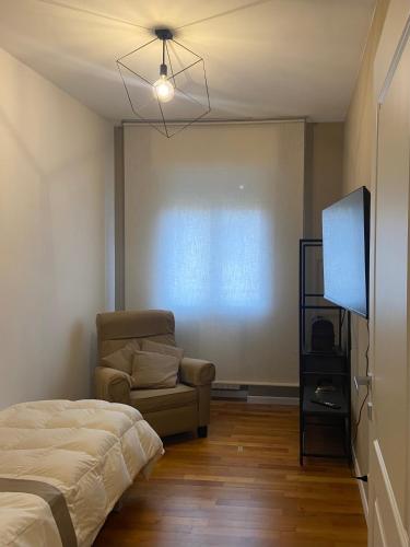 a bedroom with a bed and a chair and a flat screen tv at Giotto 2 Guesthouse in Maserà di Padova
