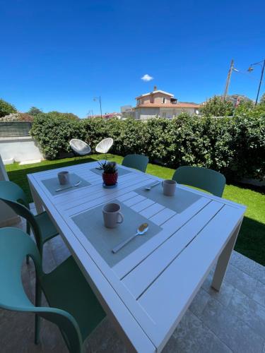 een witte tafel met kopjes en bestek erop bij Casa Fralia in Olbia
