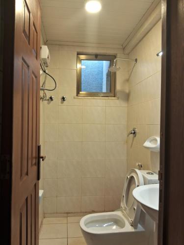 a bathroom with a toilet and a sink and a window at BA Viila in Addis Ababa