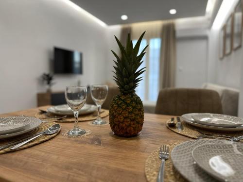 a pineapple sitting on a wooden table with plates and glasses at The Heidi's Central House in Kos Town