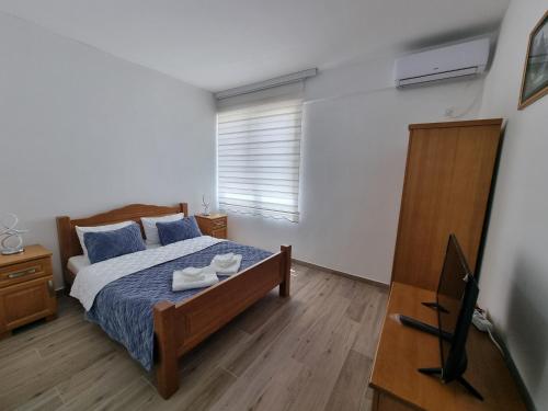 a bedroom with a bed with blue pillows and a television at City Square Apartments in Plav