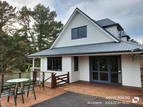 a house with a deck with chairs and a table at 别墅中的一间客房 in Auckland