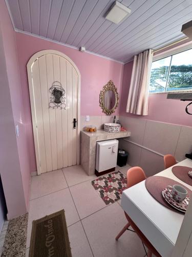 a pink room with a door and a table at La vita hospedaria studio Rosa in Nova Veneza