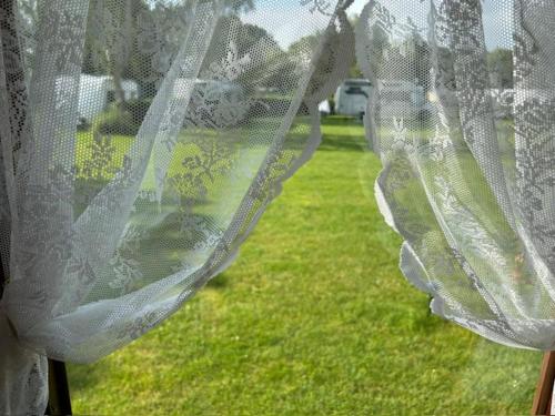 a view of a window with lace curtains at Pipowagen in Sleen