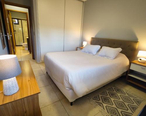 a bedroom with a large white bed with two pillows at Drummond Apartments in Ciudad Lujan de Cuyo