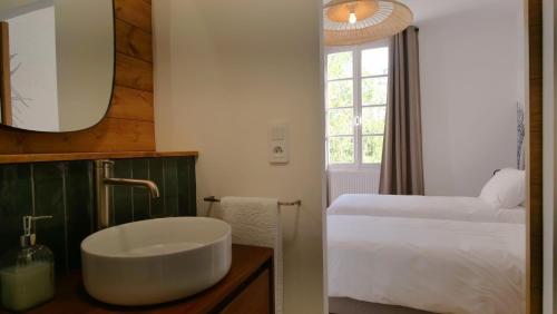a bathroom with a sink and a bed and a window at Mas Labrugade in Lebreil