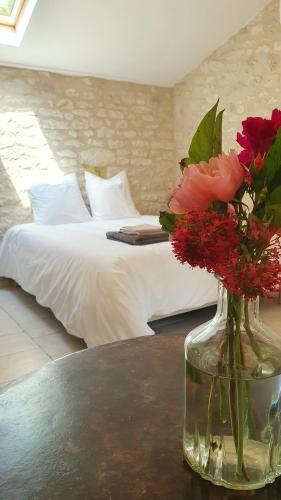 a vase of flowers on a table with a bed at Mas Labrugade in Lebreil