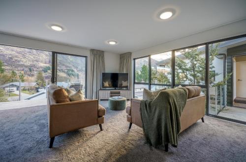 a living room with two chairs and a tv and windows at Redfern Retreat in Queenstown