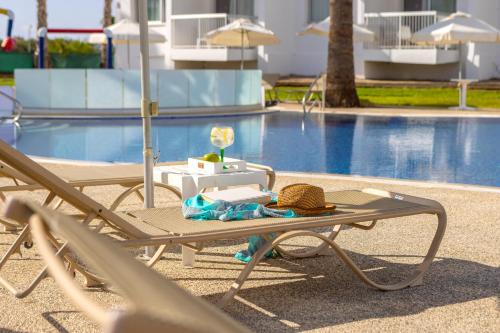a picnic table with a hat next to a pool at Papantonia Hotel in Protaras
