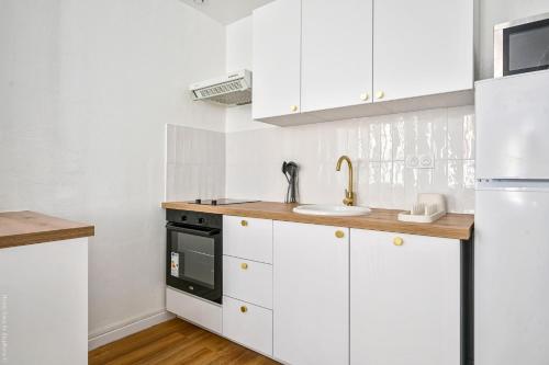 une cuisine avec des armoires blanches et un évier dans l'établissement Lumineux T3 refait à neuf dans le Vieux Toulon Centre, à Toulon