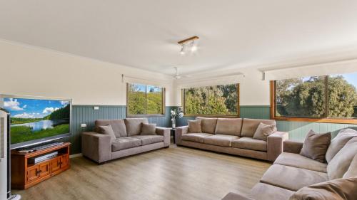 a living room with two couches and a flat screen tv at Treetop Retreat - Family Escape with Pool in Metung