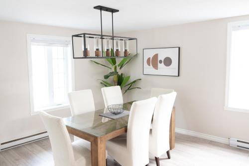 a dining room with a glass table and white chairs at 3min du ferry Maison bien équipée Parking et Jardin in Lévis