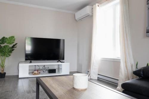 a living room with a flat screen tv on a wall at 3min du ferry Maison bien équipée Parking et Jardin in Lévis
