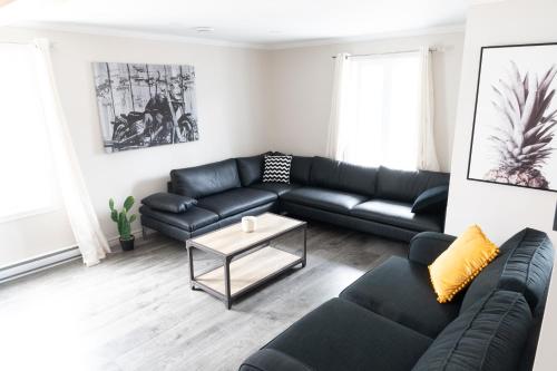 a living room with a black couch and a table at 3min du ferry Maison bien équipée Parking et Jardin in Lévis