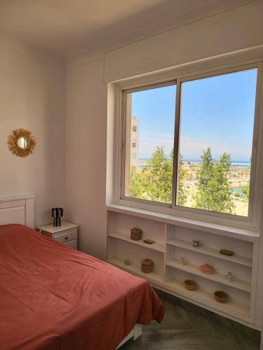 a bedroom with a bed and a large window at Appartement front de mer Tanger in Tangier