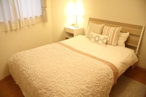 a bedroom with a large white bed with a lamp at Liaison House Universal Gateway in Osaka