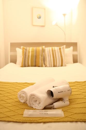 a bed with a pile of towels on it at Liaison House Universal Gateway in Osaka