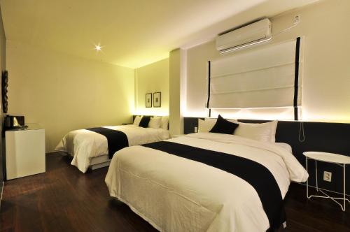 a hotel room with two beds with white and black sheets at Gout Stay in Daegu