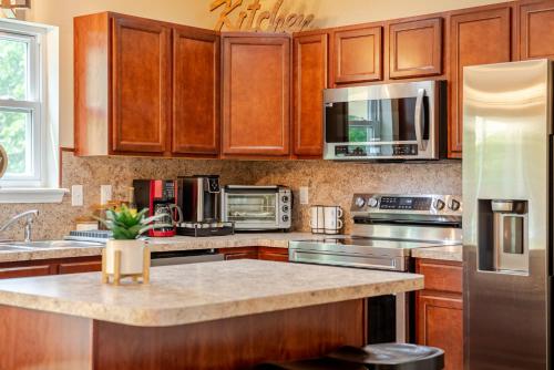 a kitchen with wooden cabinets and stainless steel appliances at Huge villa in the hearth of Poconos near all. in Long Pond