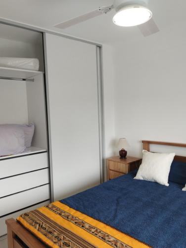 a bedroom with a bed with a blue comforter at Departamento golf Hurlingham in Hurlingham