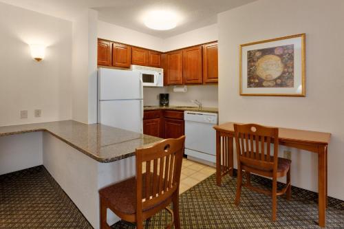 a kitchen with a table and two chairs and a counter at Staybridge Suites Allentown Airport Lehigh Valley by IHG in Allentown
