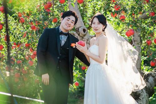 a bride and groom standing in front of an apple tree at 果樹園グランピングヴィラHARASAWA in Minakami