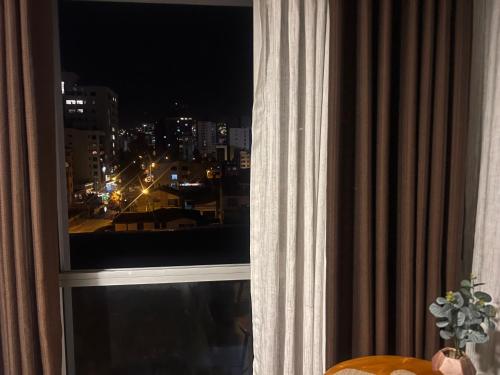 a window with a view of a city at night at Moderno y cómodo estudio con espacio de trabajo in Cochabamba