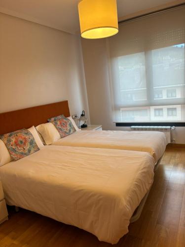 a bedroom with two beds and a large window at Apartamento Oviedo Naranco in Oviedo
