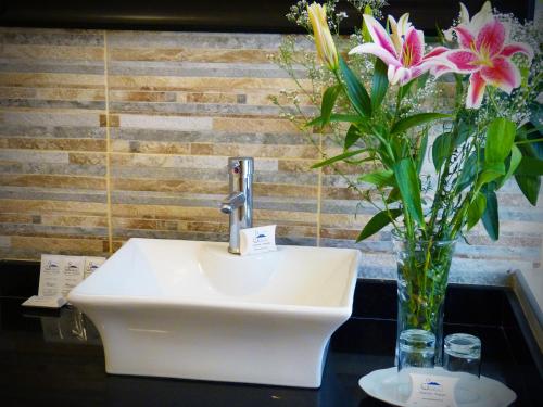 a white sink with a vase of flowers on a table at Majestad Hotel Boutique in Arequipa
