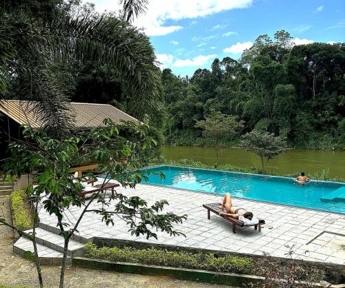 a person laying on a chaise lounge next to a swimming pool at Kandy Cabana in Kandy